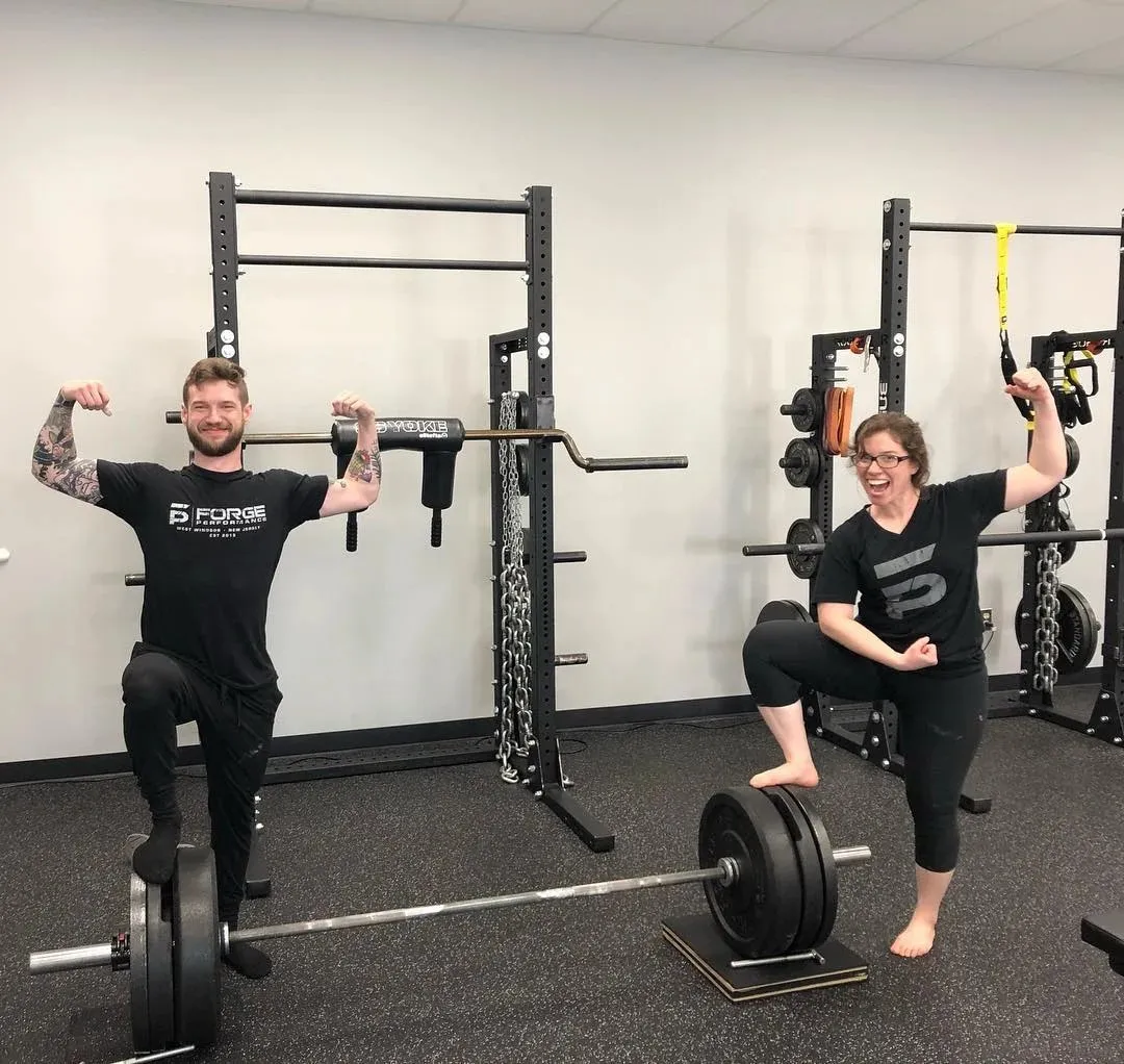 How Exercise for Stress Relief Boosts Your Mood 1 Two people flexing muscles beside a barbell in a gym setting