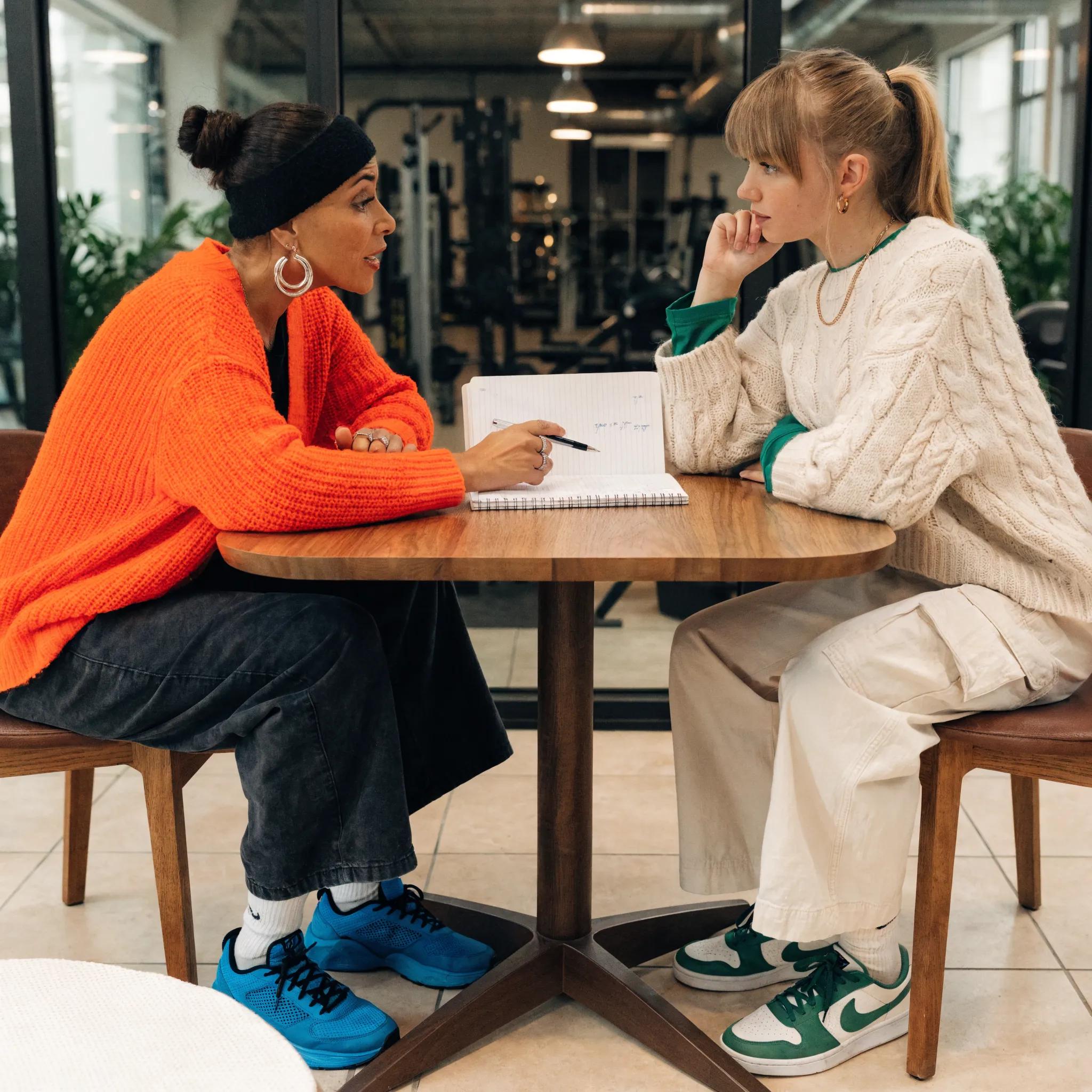Personal trainer and client discussing workout goals for improved accountability